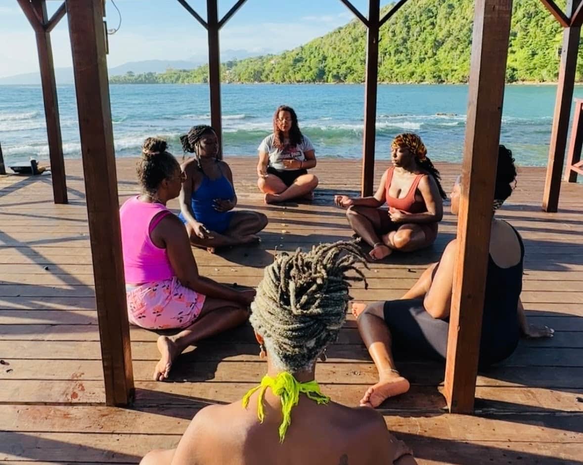 group seated in meditation on deck by water in jamaica