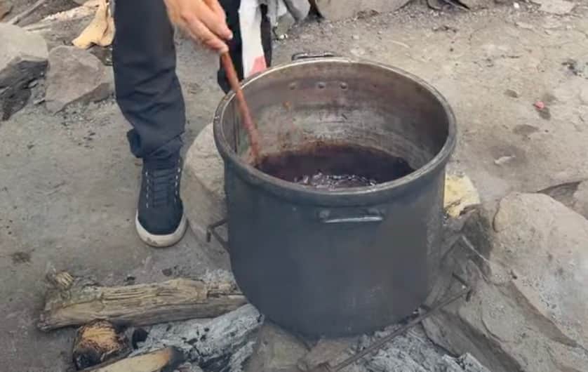 stirring pot of ayahuasca over firewood (landscape)
