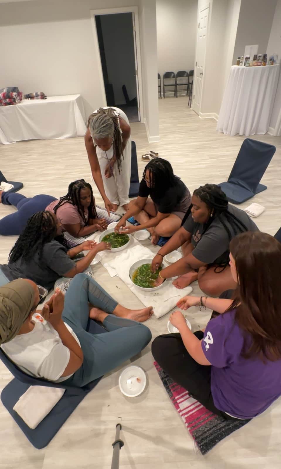 Althea and a group seated around bowls of leaves during an indoor learning activity